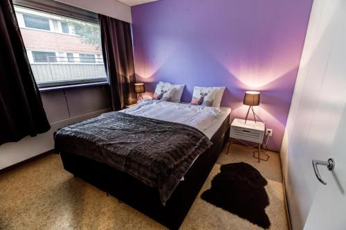 ソダンキュラにあるKuukkeli Apartments Sodankyläの紫色のベッドルーム(ベッド1台、窓付)