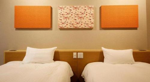 two beds in a room with paintings on the wall at Ako Park Hotel in Ako