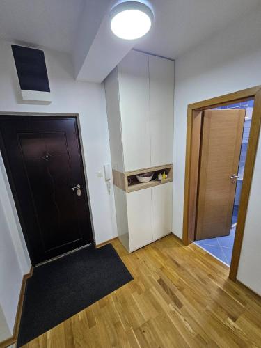 an empty room with a black door and a room with wooden floors at BPMNEdailyrent in Bijelo Polje