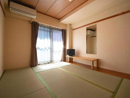 a living room with a large window and a television at Business Hotel Wako in Ichinomiya