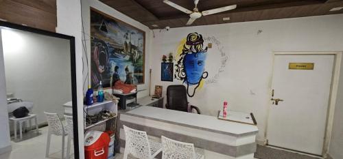 a room with a painting on the wall and chairs at Hotel 1947 & Labella Rooftop Cafe in Pushkar