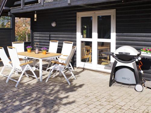 een grill op een patio met een tafel en stoelen bij 6 person holiday home in Rømø in Vesterhede