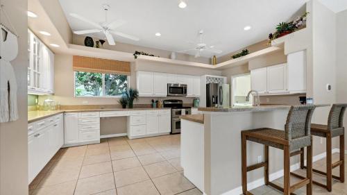 a kitchen with white cabinets and a bar with stools at GRH11408 - Charlotte Harbor Area - 3 Bed 3 Baths Villa in Rotonda