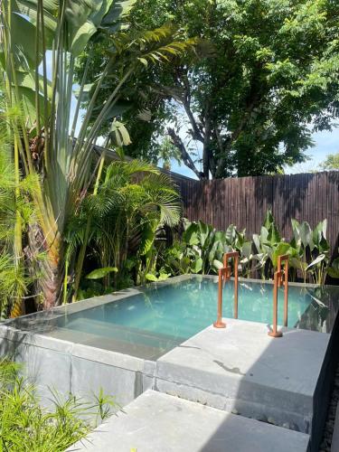 a swimming pool in a garden with trees and a fence at Ancient Huế Garden Houses in Hue