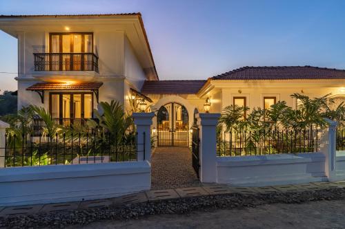 a white house with a fence in front of it at Villa Lumi, Villas By Noor in Aldona