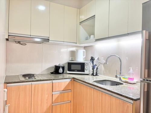 a kitchen with a sink and a microwave at The Mactan Newtown Condo Staycation in Sampong