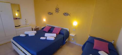 a bedroom with two beds with blue sheets and pink pillows at Summer Rooms Caucana in Punta Secca