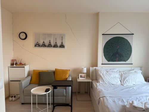 ein Schlafzimmer mit einem Bett, einem Sofa und einer Uhr in der Unterkunft Cozy7 Living in Bangkok60 m to MRTnear chatuchank in Ban Bang Khwang