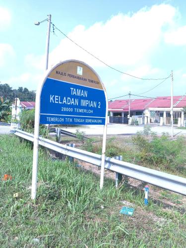a sign in the grass in front of a street at Homestay Annur Impian Temerloh With WIFI & NEXFLIX in Temerloh