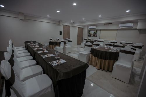 a banquet hall with tables and white chairs at Biznotel by Pride Surat in Surat