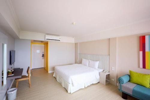 a bedroom with a white bed and a couch at Hua Hin Grand Hotel and Plaza - SHA Extra Plus in Hua Hin