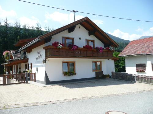 a white house with a balcony with flowers at Apartment in Tröpolach near Nassfeld in Tröpolach
