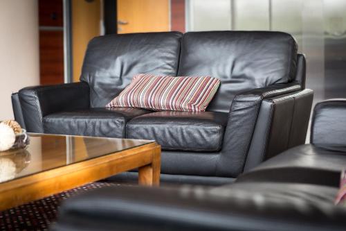 a black leather couch with a striped pillow in a living room at Hotel Lille Europe in Lille