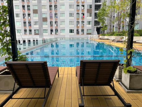 zwei Stühle neben einem großen Pool in der Unterkunft Cozy7 Living in Bangkok60 m to MRTnear chatuchank in Ban Bang Khwang