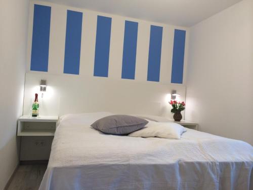 Schlafzimmer mit einem Bett mit blauen und weißen Streifen an der Wand in der Unterkunft Ferienzimmer Lütt in Juliusruh