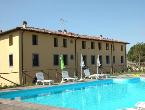 un hotel con una piscina con sillas y sombrillas en Residence Giuly Rosselmini, en Pieve di Santa Luce