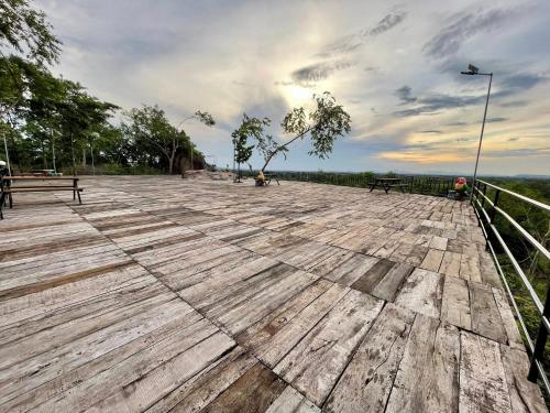 a wooden deck with benches and a cloudy sky at Thisak Resort Cheung phnom kulen in Siem Reap