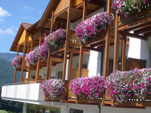 un bâtiment avec beaucoup de fleurs sur les balcons dans l'établissement Hotel Lindnerhof, à San Lorenzo di Sebato
