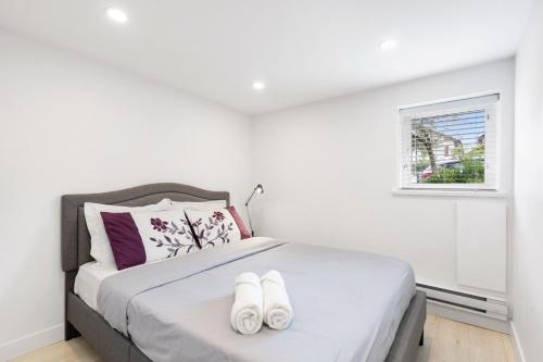 a bedroom with a bed with two white slippers on it at Callister BNB in Vancouver