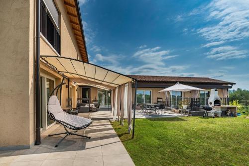 a patio with a chair on a lawn at Italianflat - FREE parking, Salted Swimmingpool - Casa Ulivi del Garda in Castion Veronese
