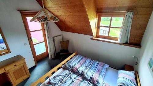a small bedroom with a bed and two windows at FerienFleckl in Warmensteinach