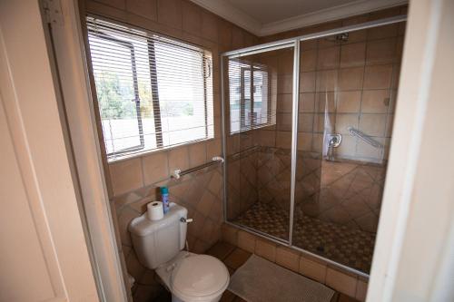 a bathroom with a toilet and a glass shower at Weavers Nest Guesthouse in Modimolle