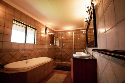 a bathroom with a tub and a sink at Weavers Nest Guesthouse in Modimolle