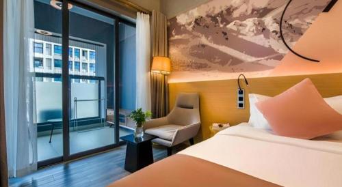 a bedroom with a bed and a chair and a window at Imin Hotel in Huadu