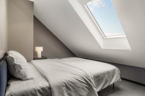a bedroom with a white bed with a skylight at Stylish Loft on Bakaroy in Haugesund