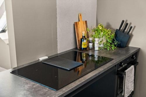 a black counter top with a bottle of wine and plants at Stylish Loft on Bakaroy in Haugesund