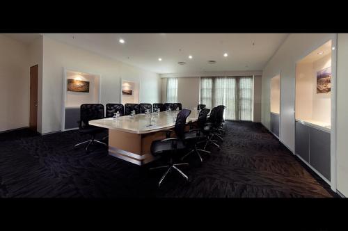 a conference room with a long table and black chairs at Abell Hotel in Kuching