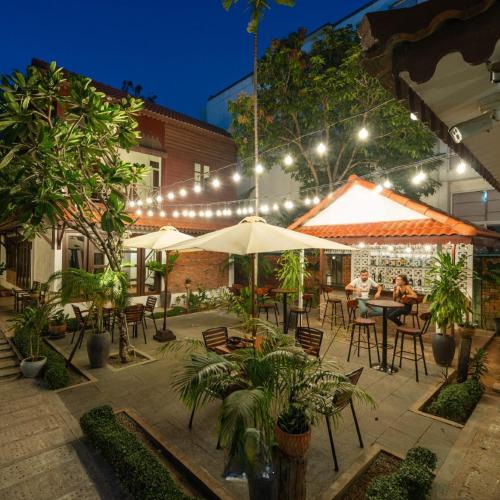 a patio with tables and chairs and umbrellas at night at Banksy's Siem Reap in Phumĭ Réach Born