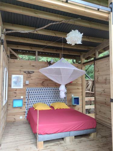 a bed in a pergola with a white umbrella at cabane entre les arbres famille in Deshaies