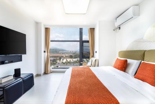 a bedroom with a large bed and a large window at Laike meisu - Sanya Longhu Phoenix Airport Branch in Sanya
