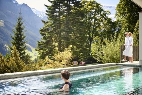 a woman swimming in a swimming pool in the mountains at Bellevue Parkhotel & Spa - Relais & Châteaux in Adelboden