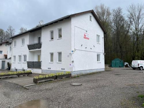 a large white building in a parking lot at ZV-Scholtz Gästehaus Eisenfelden in Winhöring