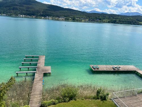 a dock on a lake with mountains in the background at Appartements Rocky Lake in Techelsberg am Worthersee