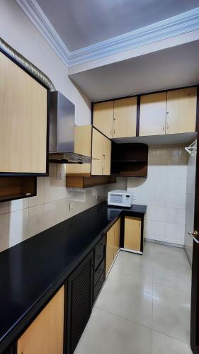 a kitchen with a black counter top and wooden cabinets at Nayra Apartment by Jaiswal House in Kolkata