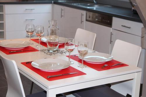 a white table with wine glasses and red napkins at Gîtes du Montois in Genech