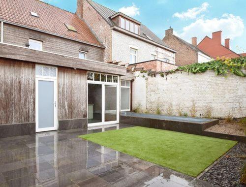a house with a courtyard with green grass at Maison Lucy In het huis van de kunstenares in Staden