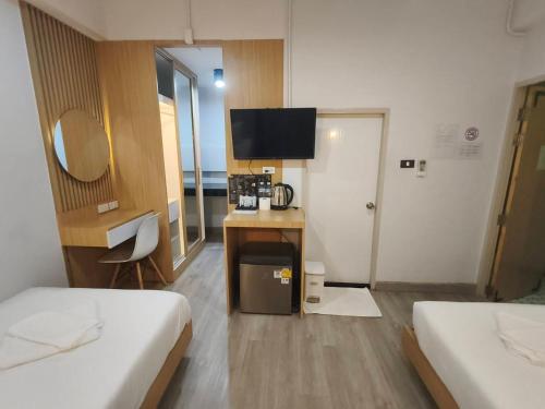 a room with two beds and a desk with a television at PG Ryoichi Hotel in Chiang Rai