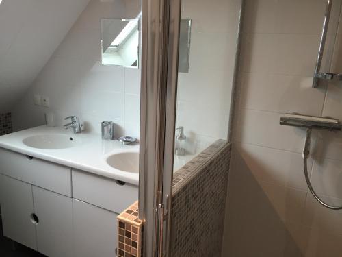 a white bathroom with a sink and a mirror at Gîtes du Montois in Genech