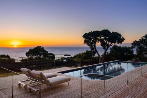 a patio with a pool and a chair and the sunset at Blanc de Noir Luxe Grandeur with Pool and Spa in Mount Martha