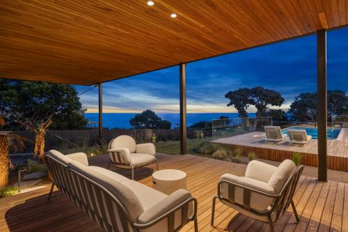 a house with a deck with chairs and a pool at Blanc de Noir Luxe Grandeur with Pool and Spa in Mount Martha