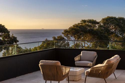 two chairs and a table on a balcony with the ocean at Blanc de Noir Luxe Grandeur with Pool and Spa in Mount Martha
