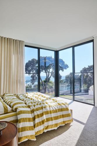 a bedroom with a yellow and white bed and large windows at Blanc de Noir Luxe Grandeur with Pool and Spa in Mount Martha