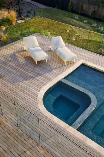 a deck with two lounge chairs and a swimming pool at Blanc de Noir Luxe Grandeur with Pool and Spa in Mount Martha