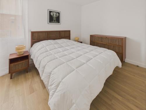 a bedroom with a large bed with a white comforter at Plein centre - Appart pour 6 avec balcon in La Teste-de-Buch