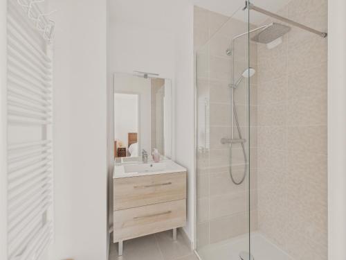 a white bathroom with a sink and a shower at Plein centre - Appart pour 6 avec balcon in La Teste-de-Buch