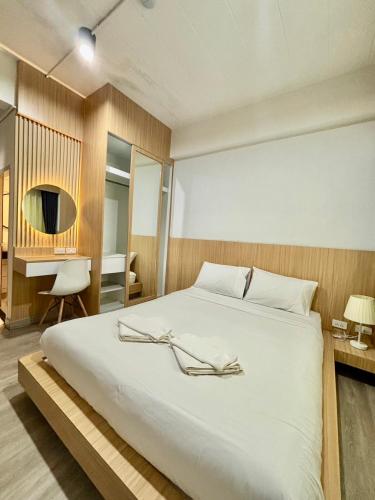 a bedroom with a large white bed and a desk at PG Ryoichi Hotel in Chiang Rai